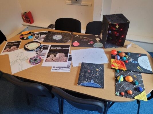 rounded wooden table on blue carpet with models of the solar system and planets