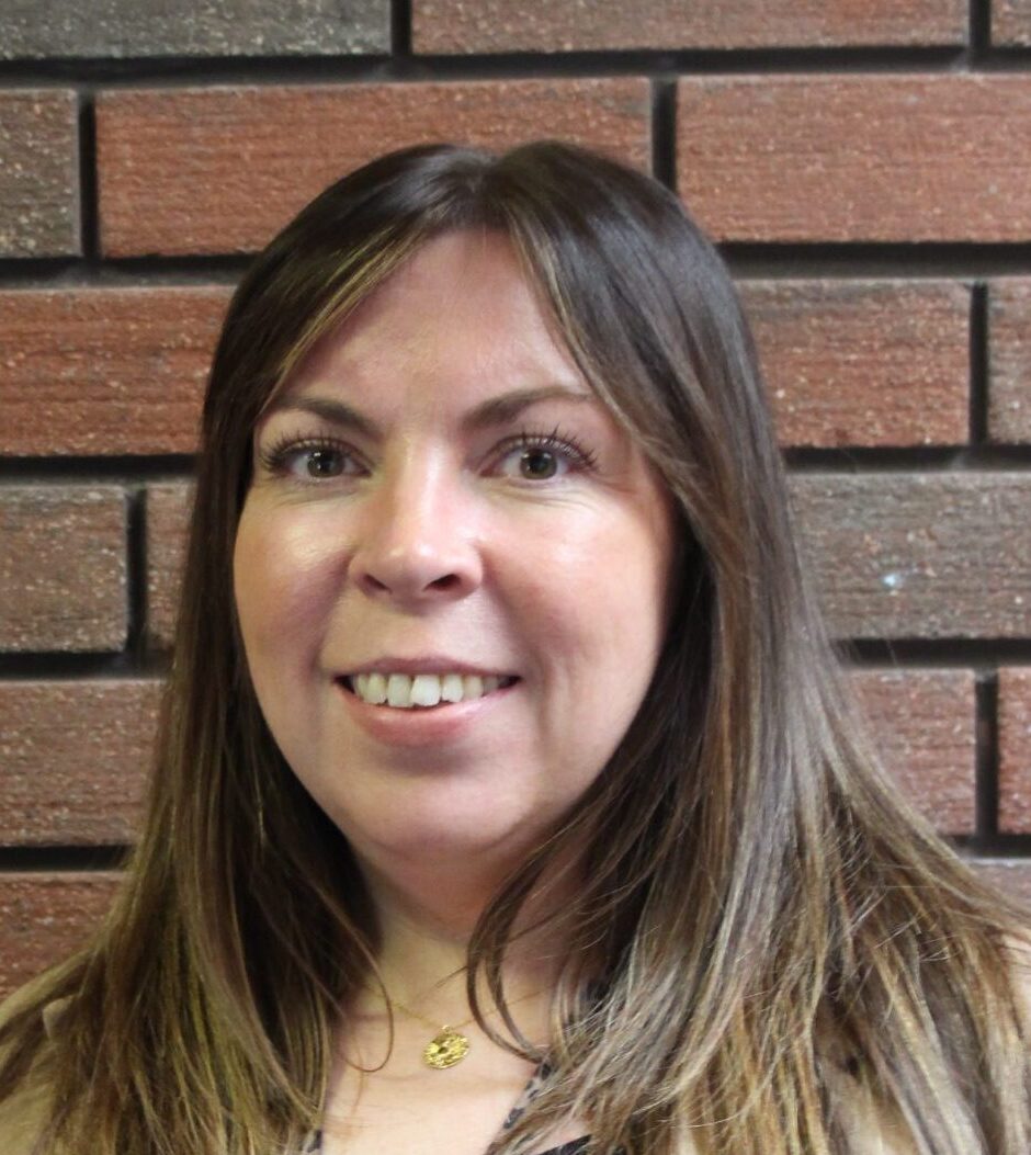 Smiling woman with brunette hair and gold necklace
