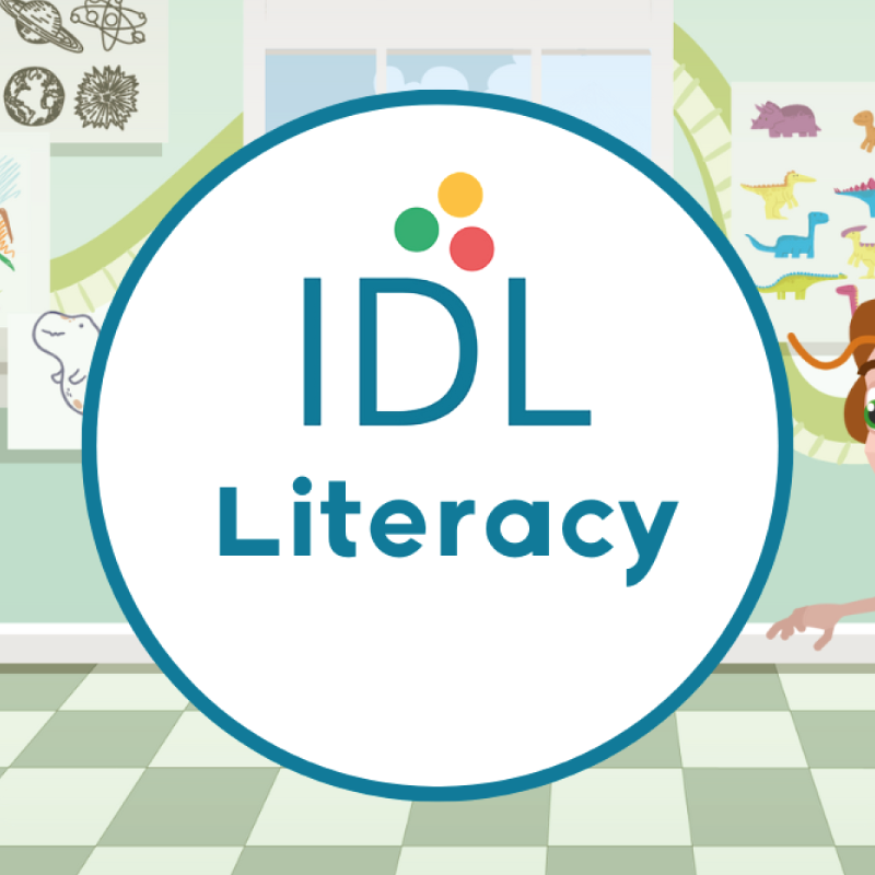 Turquoise circle with IDL logo, on a cartoon classroom background with dinosaur and space drawings on the wall