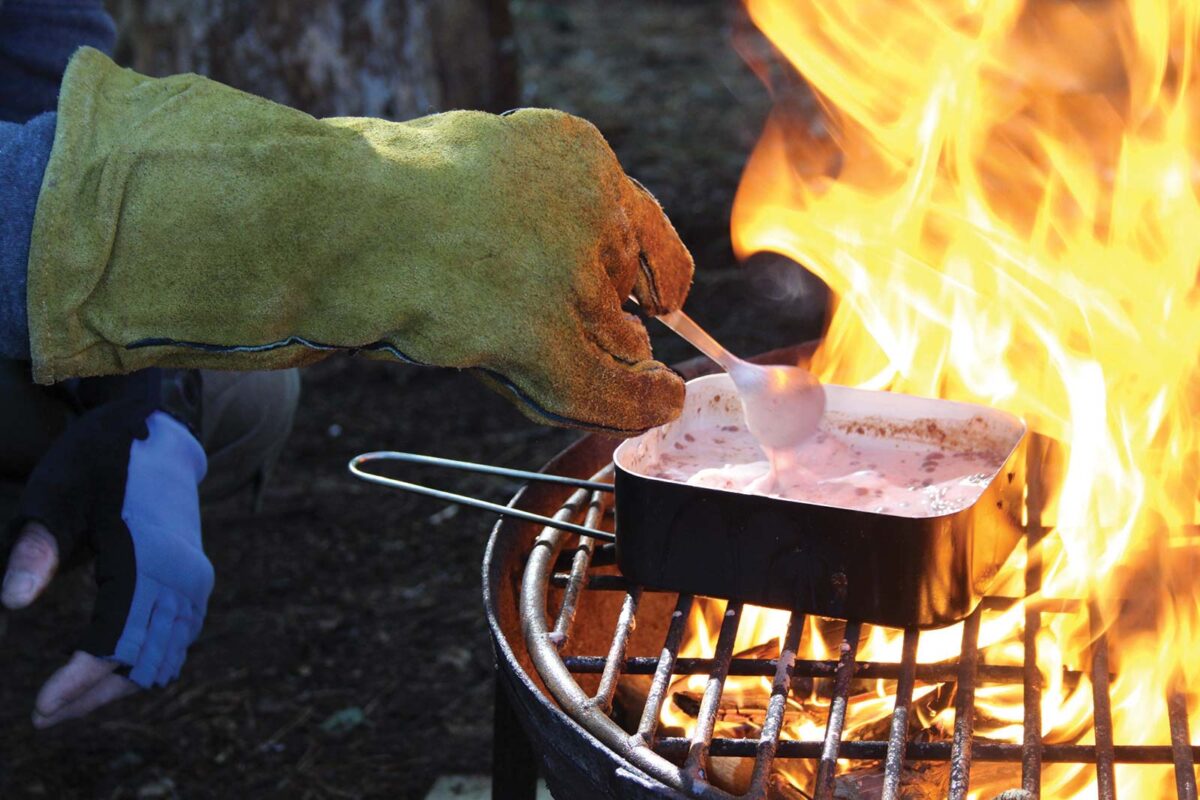 marshmallows melting over an active fire with someone using a yellow fire protective glove