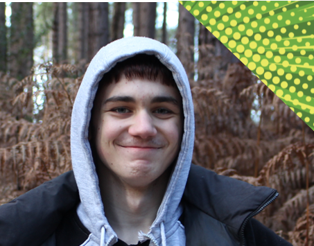 young boy wearing a hoodie, smiling in the woods